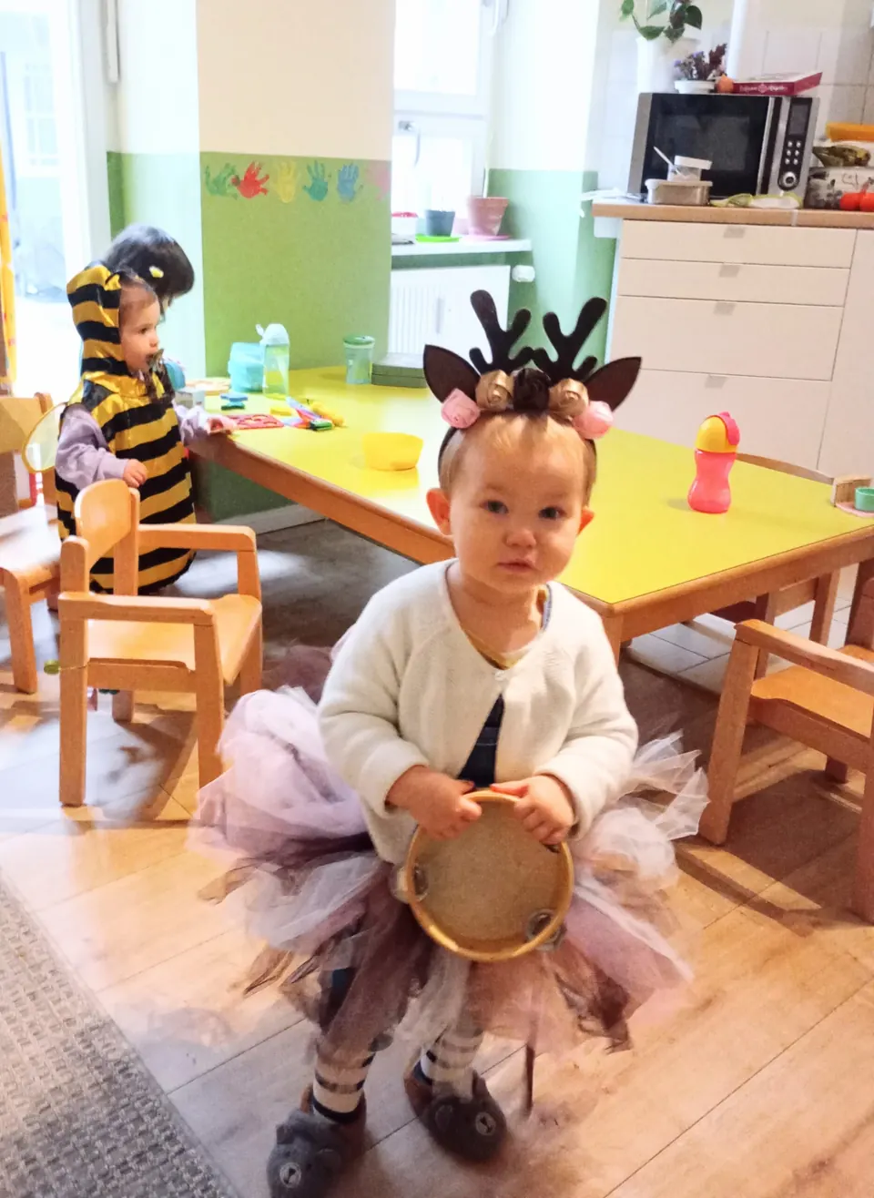 Ein Mädchen im Faschingskostüm mit Tamburin am Gruppentisch