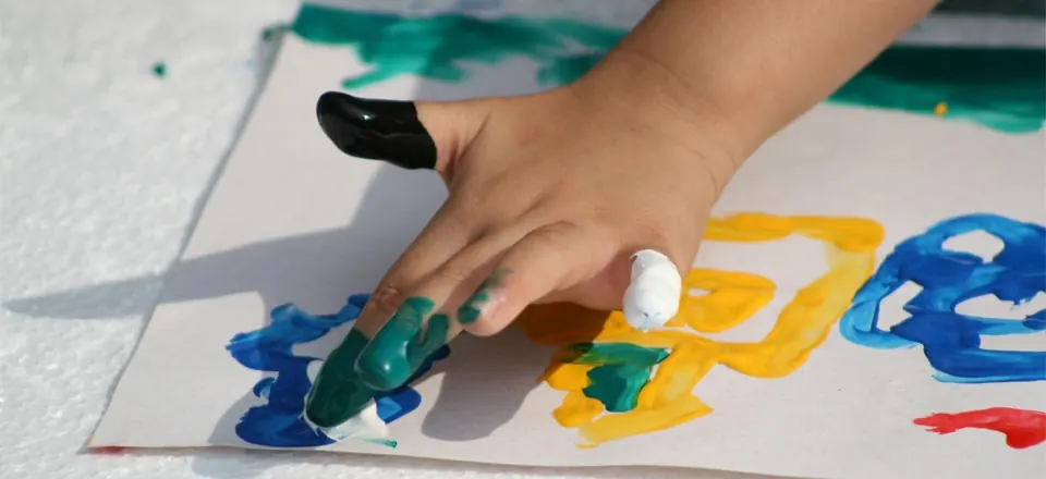 Eine Kinderhand malt mit Fingerfarben