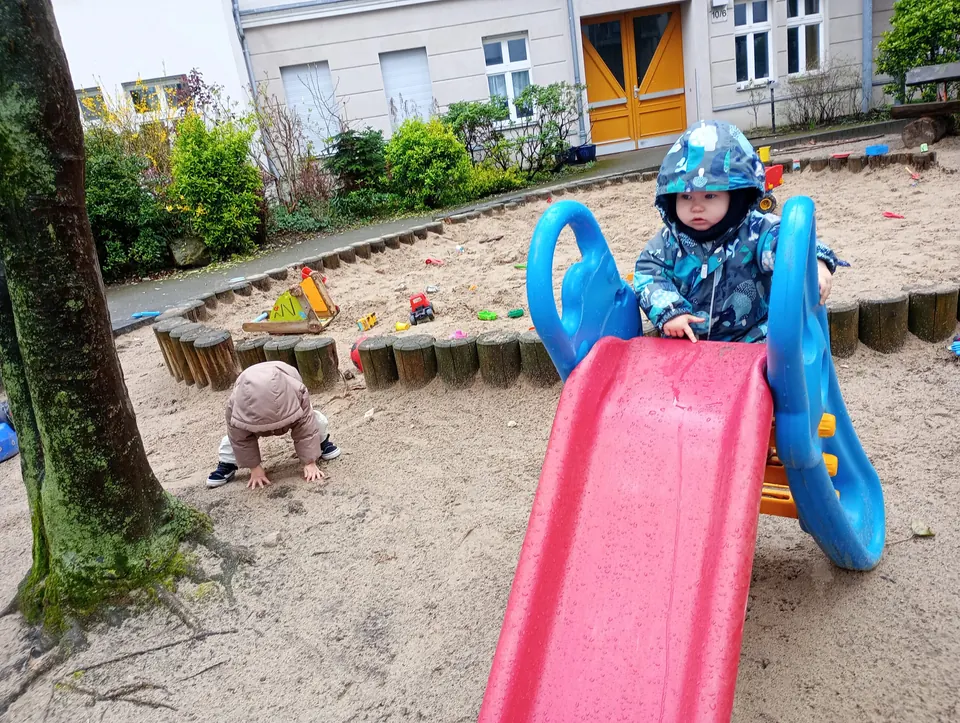 Kind im Sandkasten an der Rutsche